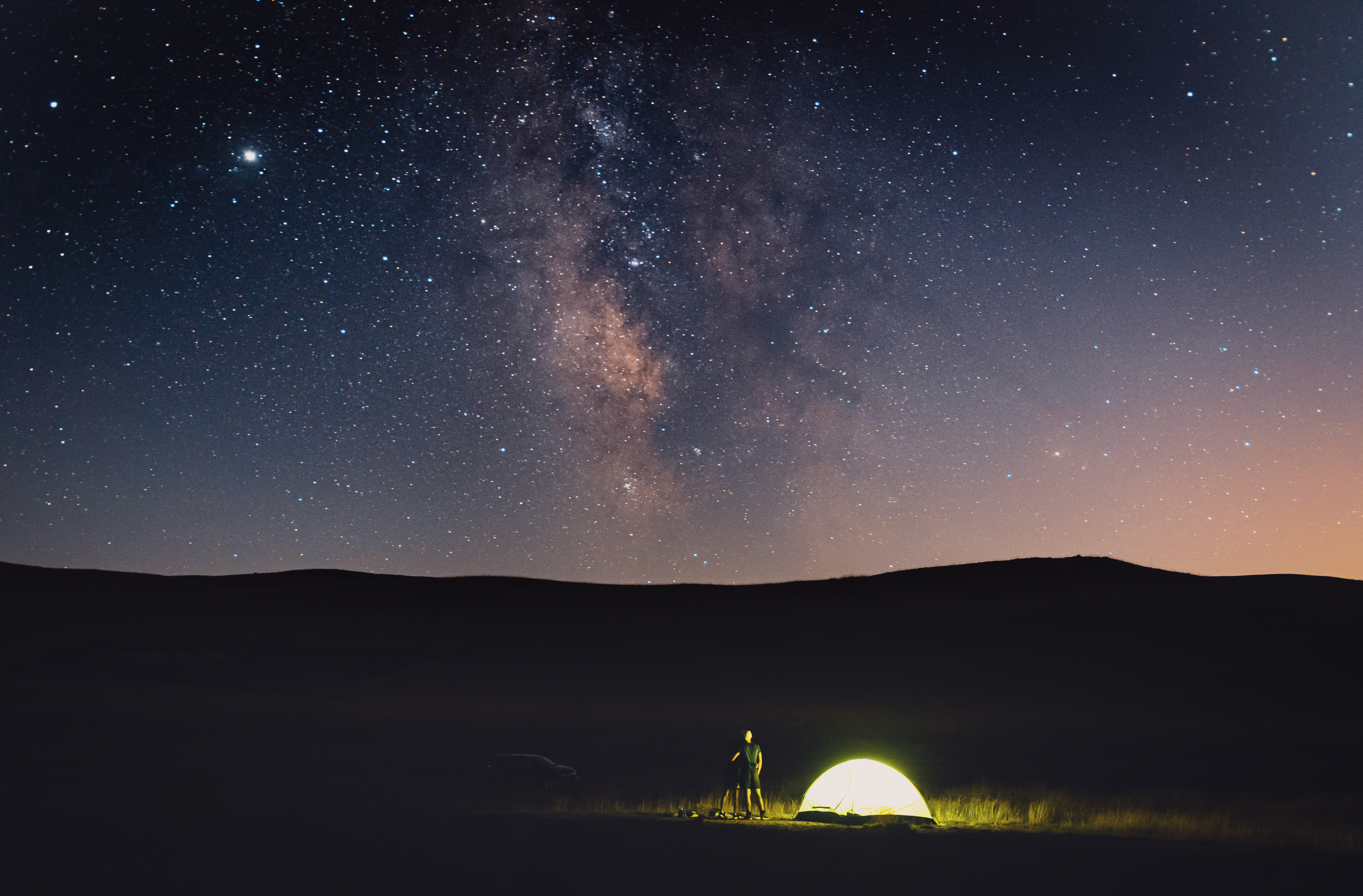 starry skies above an open field campsite